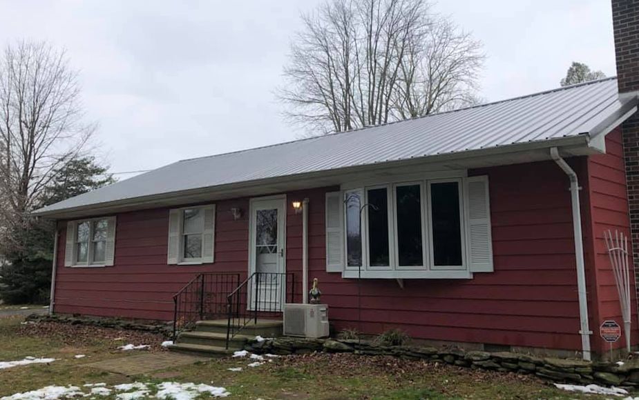 A red house with a metal roof and white shutters.