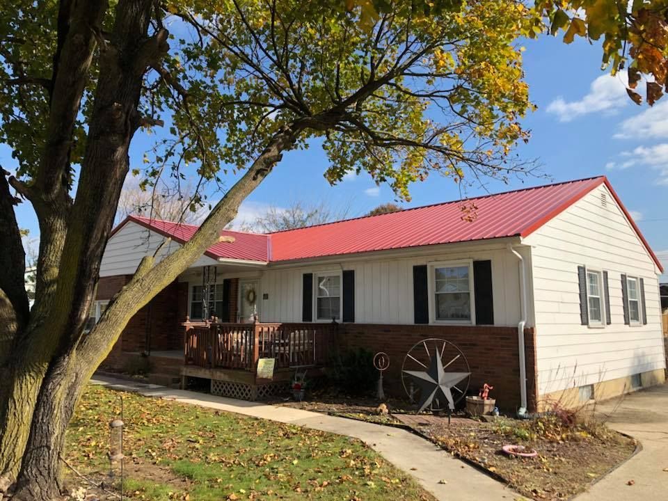 A white house with a red roof and a tree in front of it.