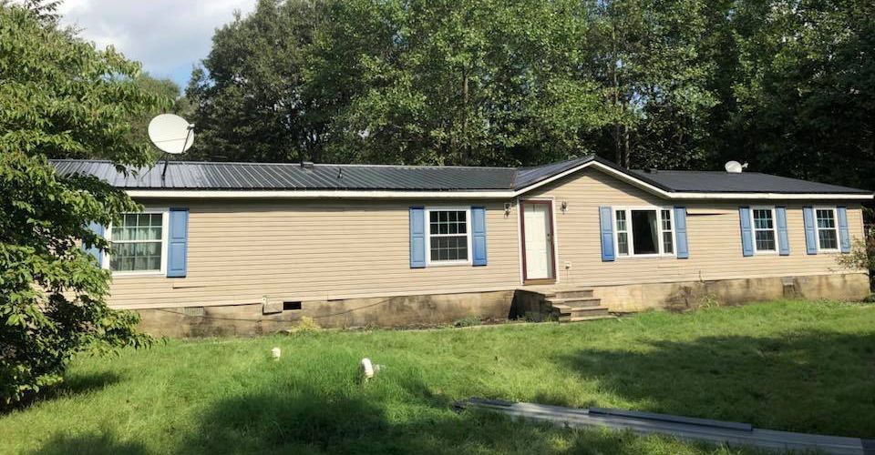 A mobile home with blue shutters and a satellite dish on the roof.