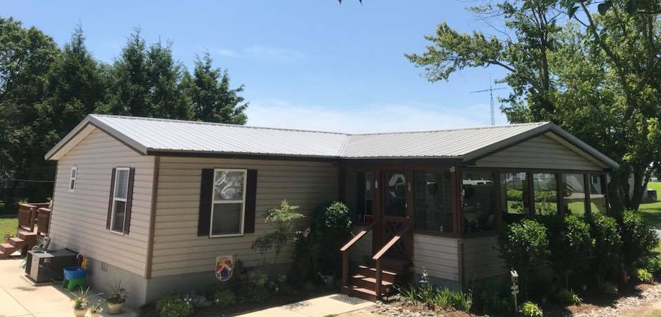 A mobile home with a metal roof and a porch.