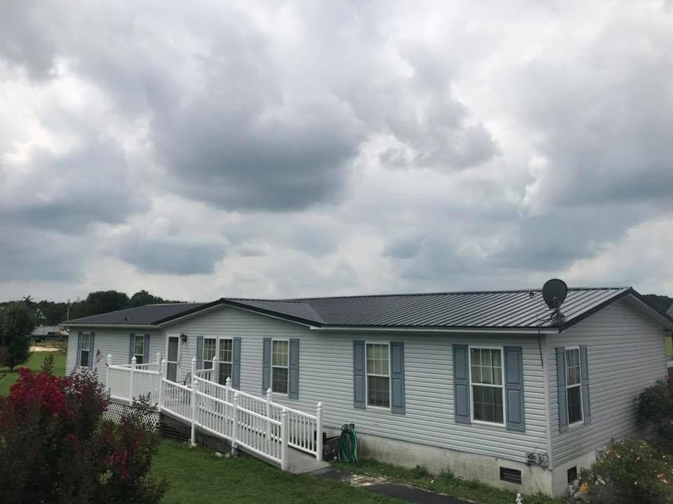A white mobile home with a black roof and a handicap ramp.