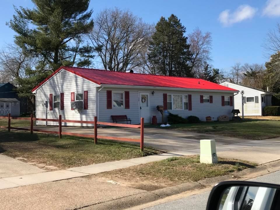 A white house with a red roof and a red fence.