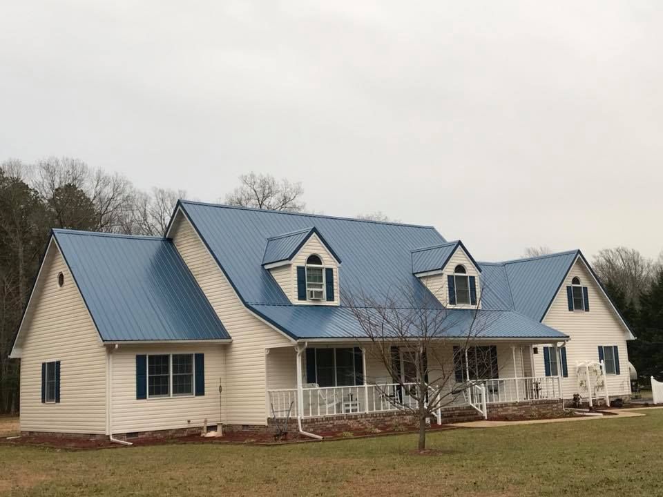 A white house with a blue roof and blue shutters