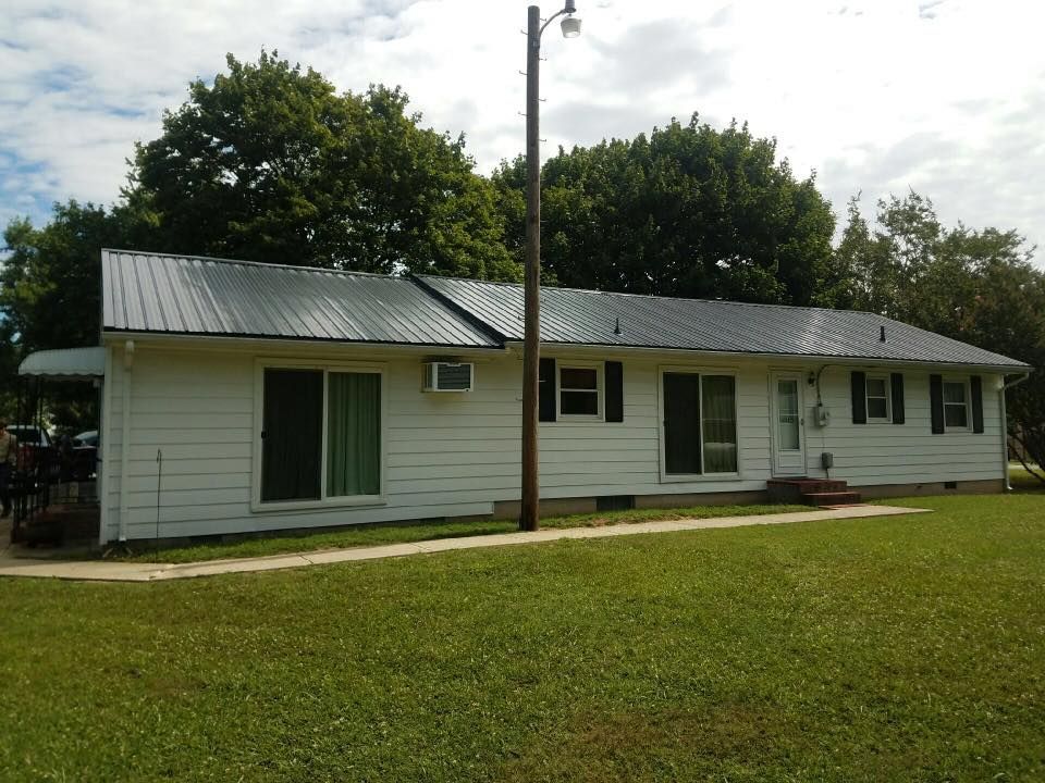 A white house with a metal roof and shutters