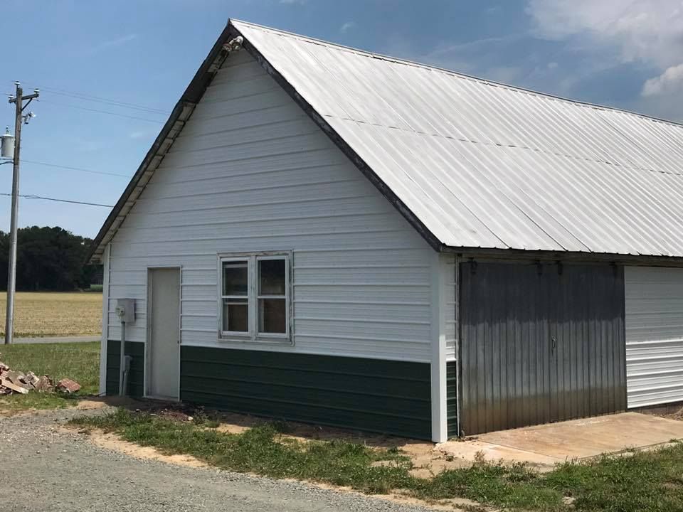 A white and green building with a metal roof