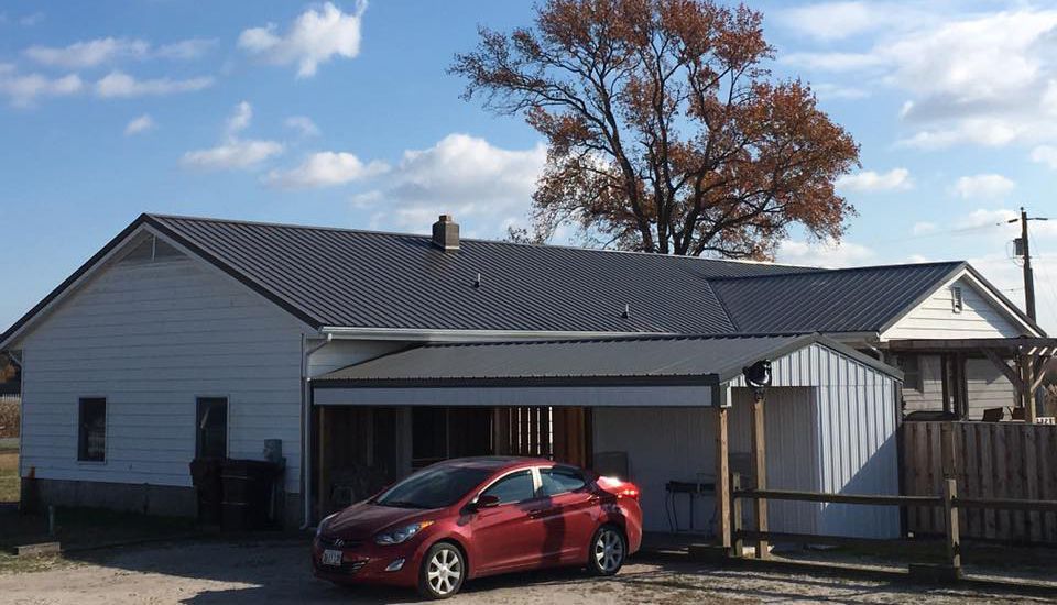 A red car is parked in front of a white house