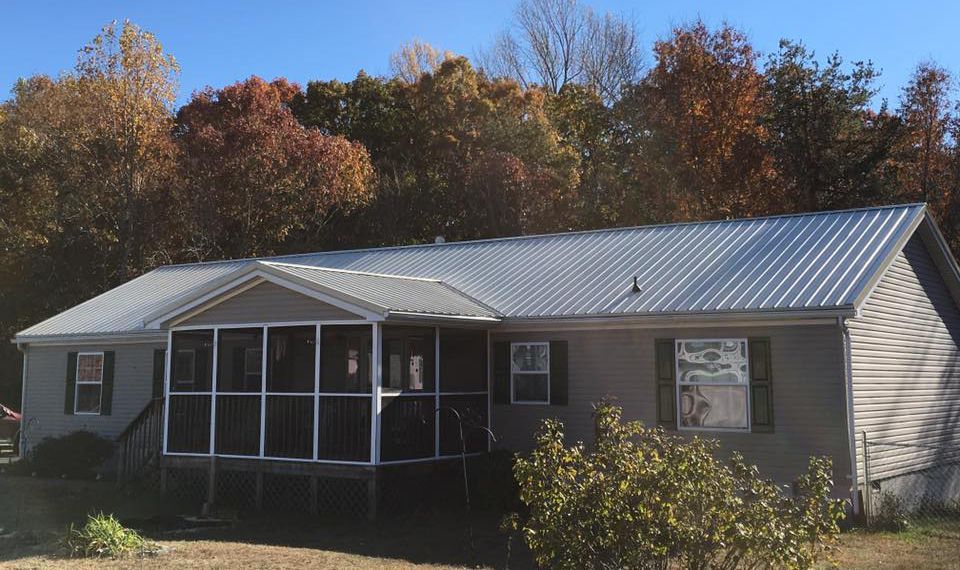 A mobile home with a screened in porch and a metal roof.