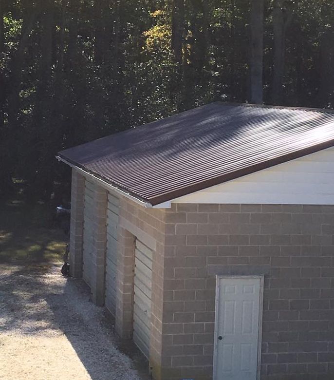 A brick garage with a brown roof and a white door