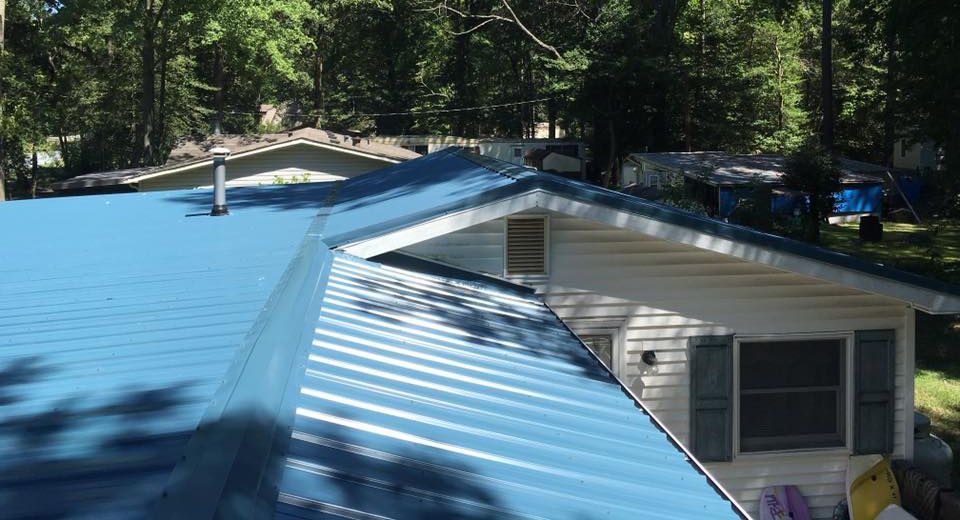 A blue metal roof is sitting on top of a white house.