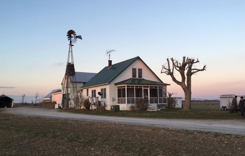 A white house with a green roof and a windmill in the background