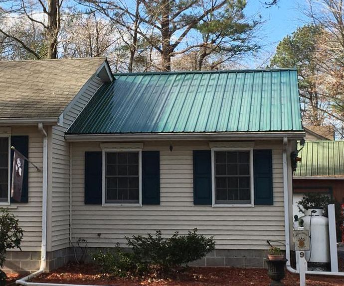 A white house with a green roof and blue shutters