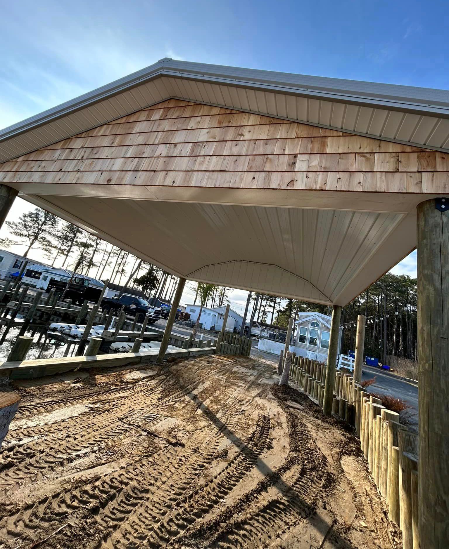 A carport with a wooden roof is sitting on top of a dirt field.