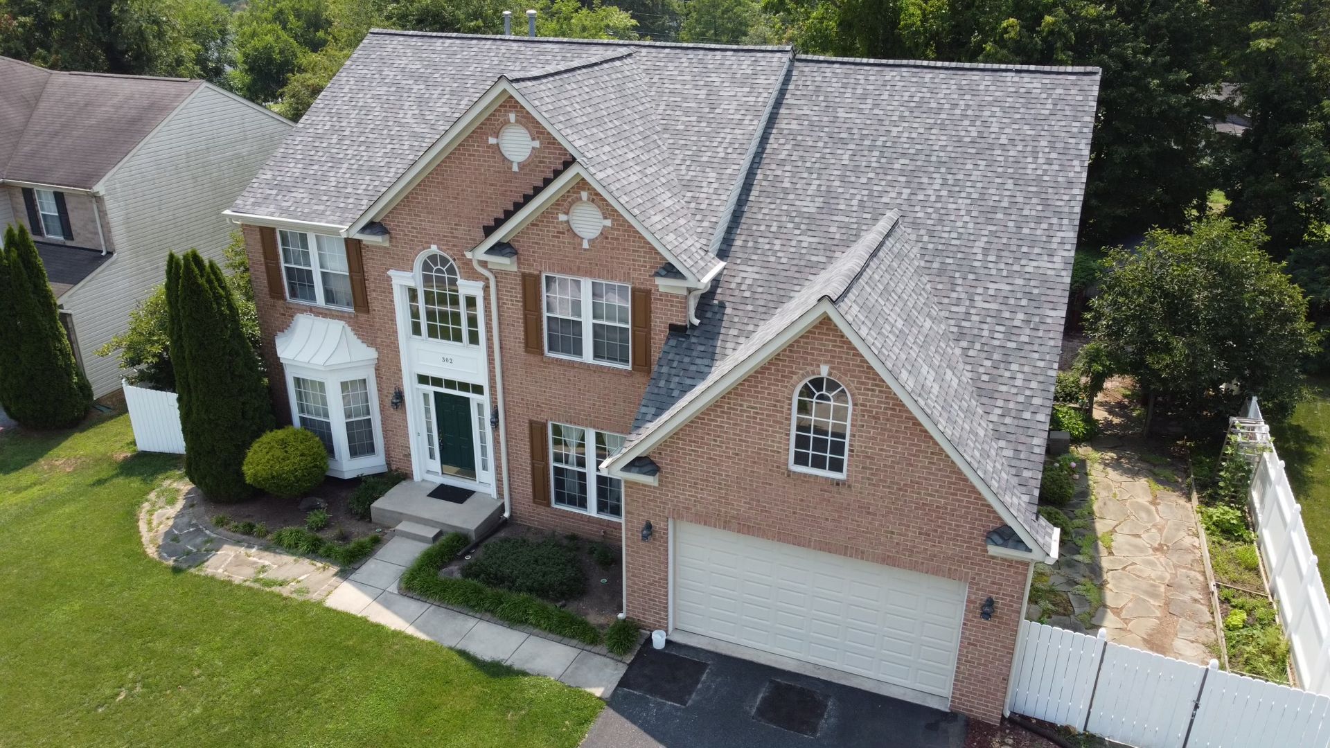 An aerial view of a large brick house with a gray roof.