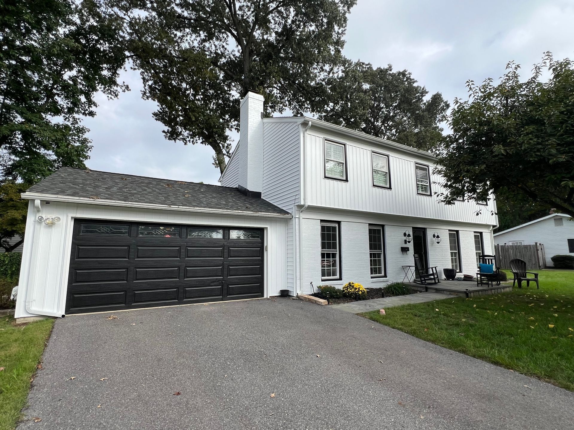 A white house with a black garage door and a driveway.
