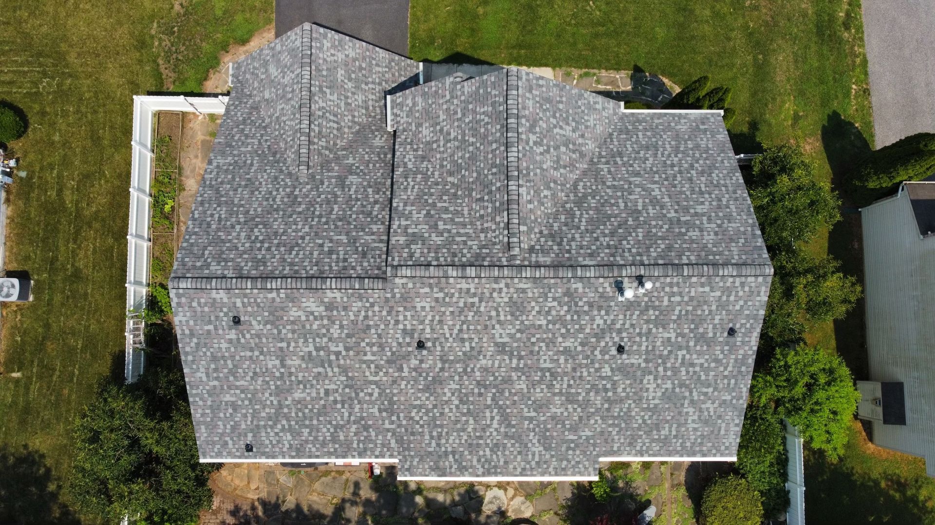 An aerial view of a house with a gray roof surrounded by grass and trees.
