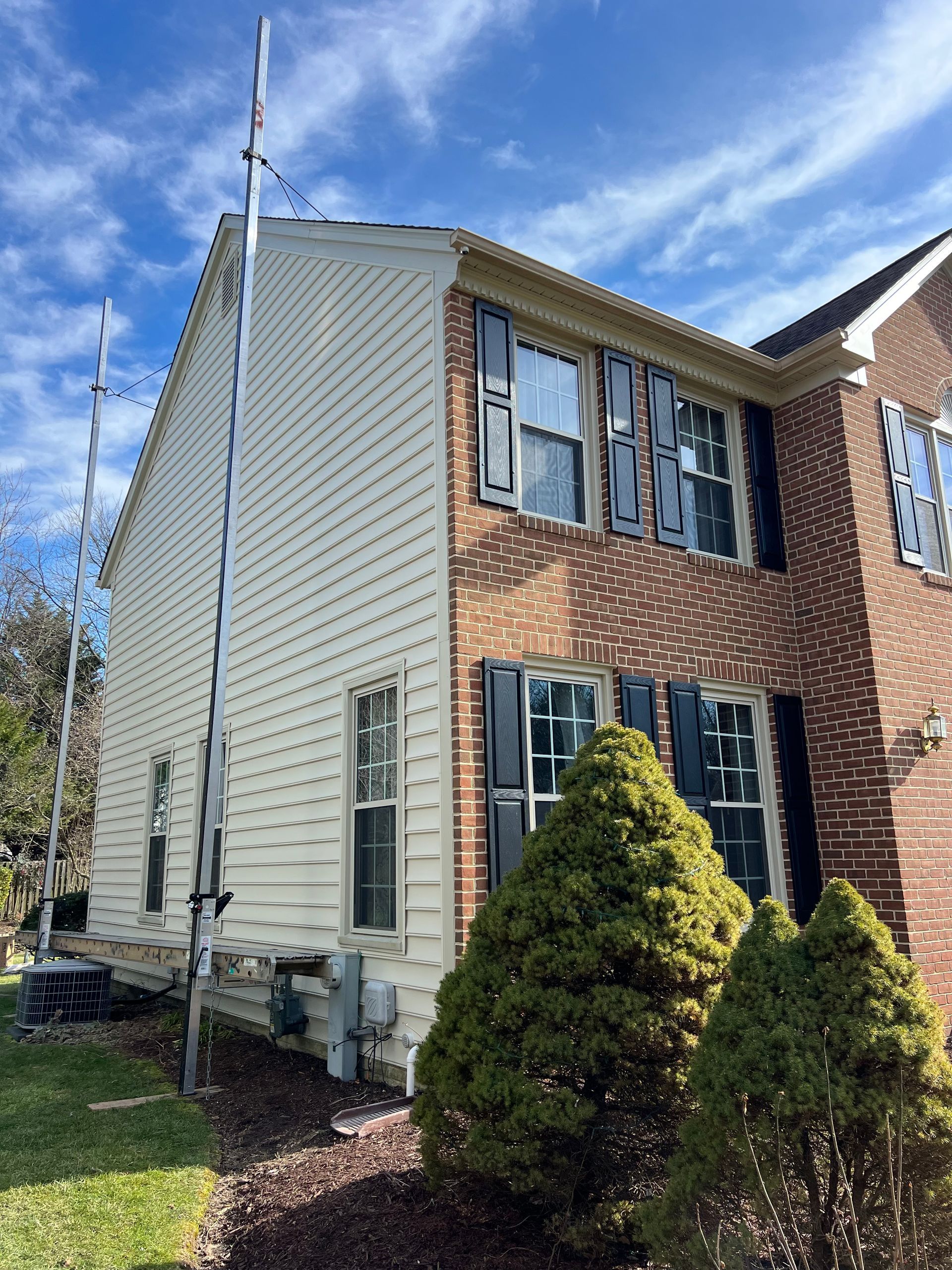 A large brick house with a white siding and black shutters.
