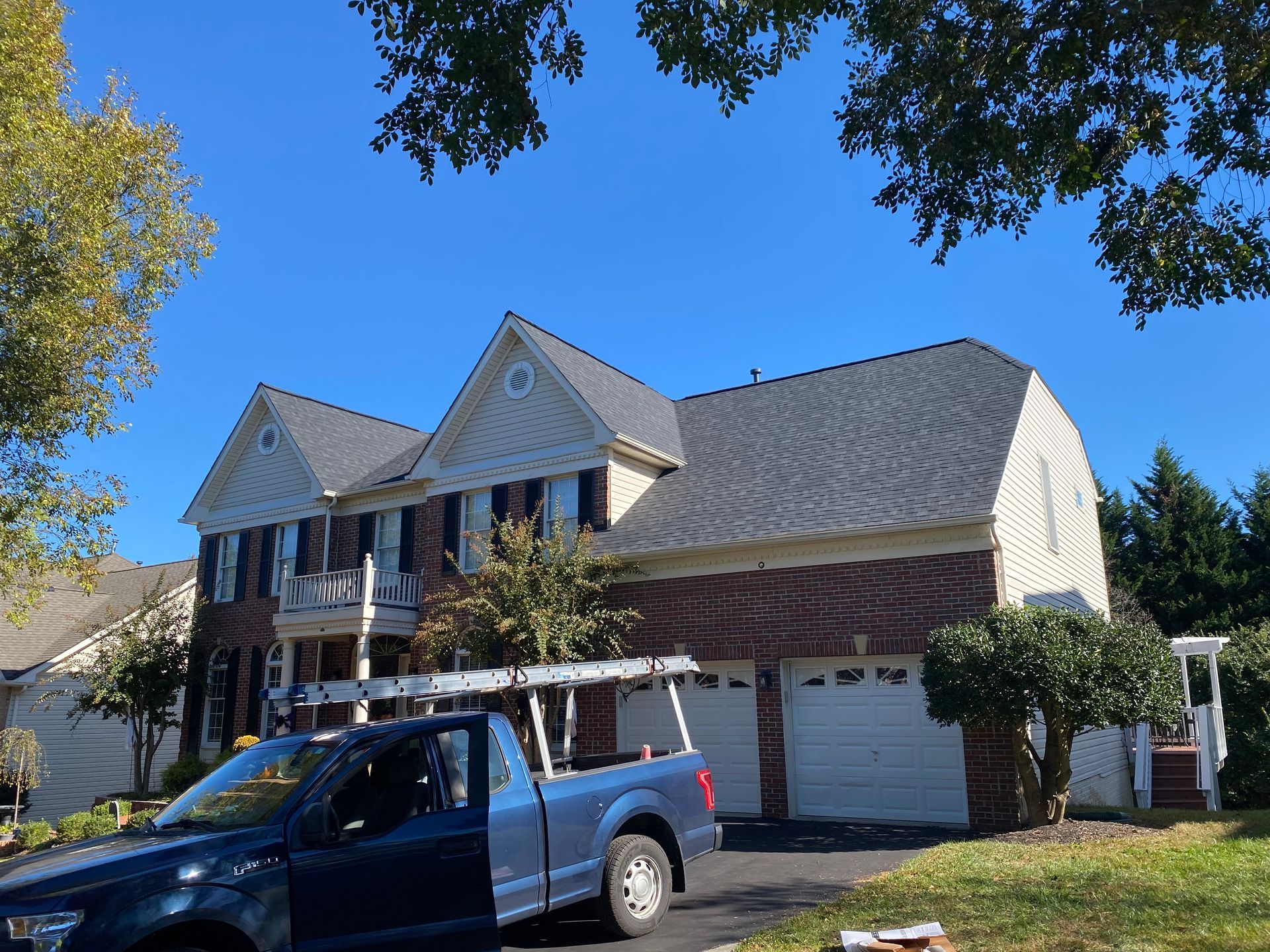 A blue truck is parked in front of a large house.