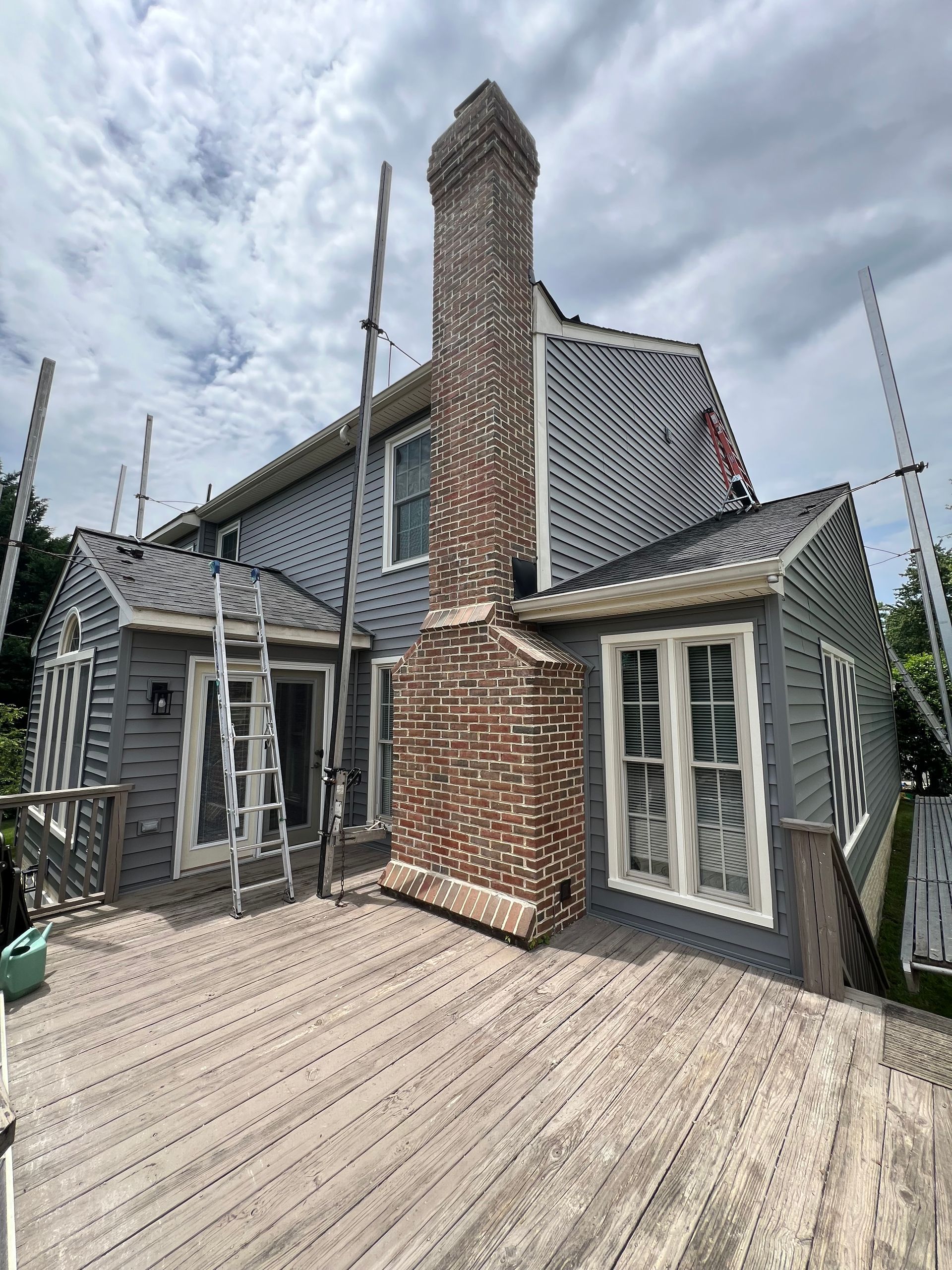 A house with a brick chimney and a wooden deck in front of it.