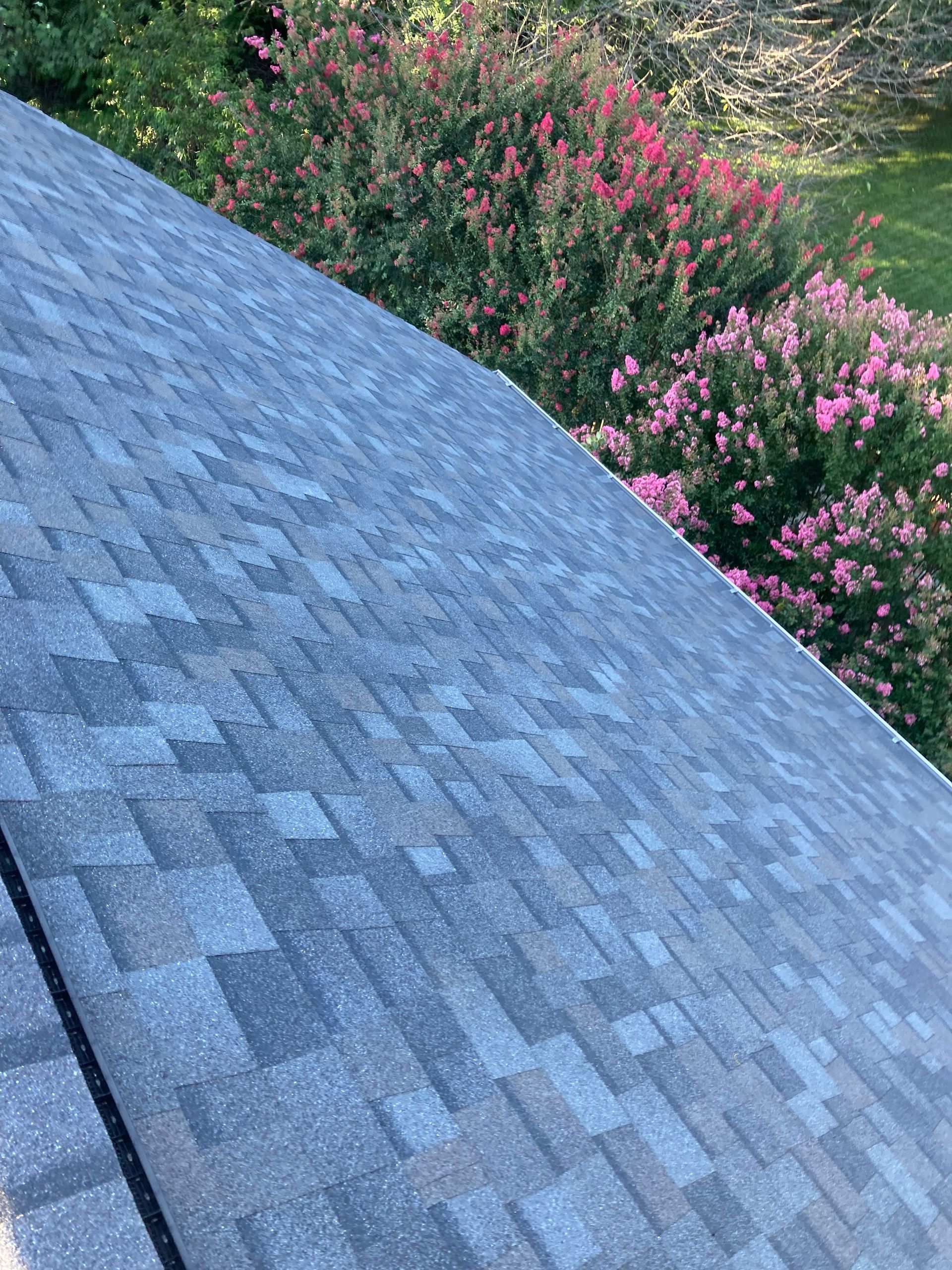 A close up of a roof with flowers in the background.
