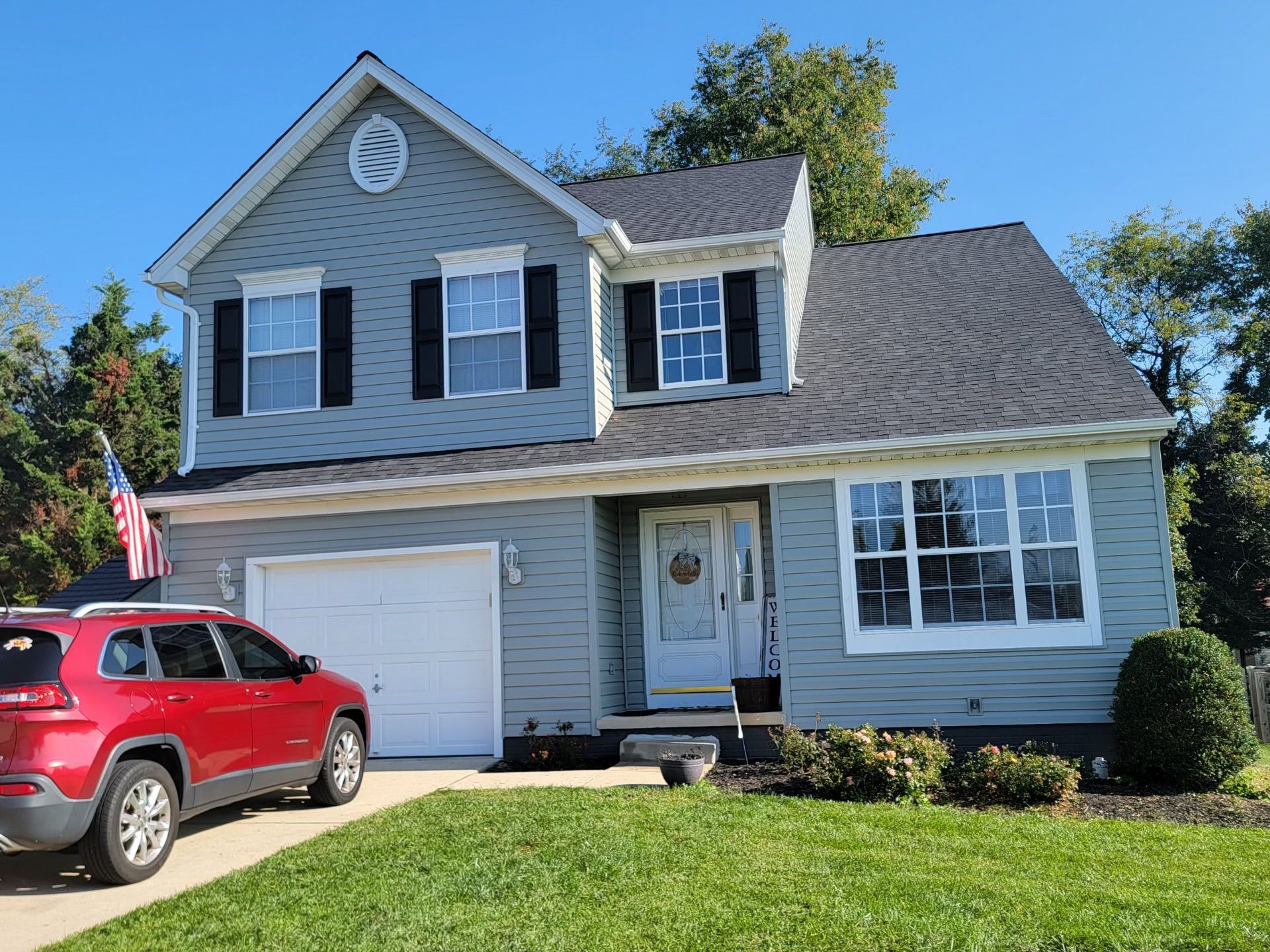 A red car is parked in front of a house.