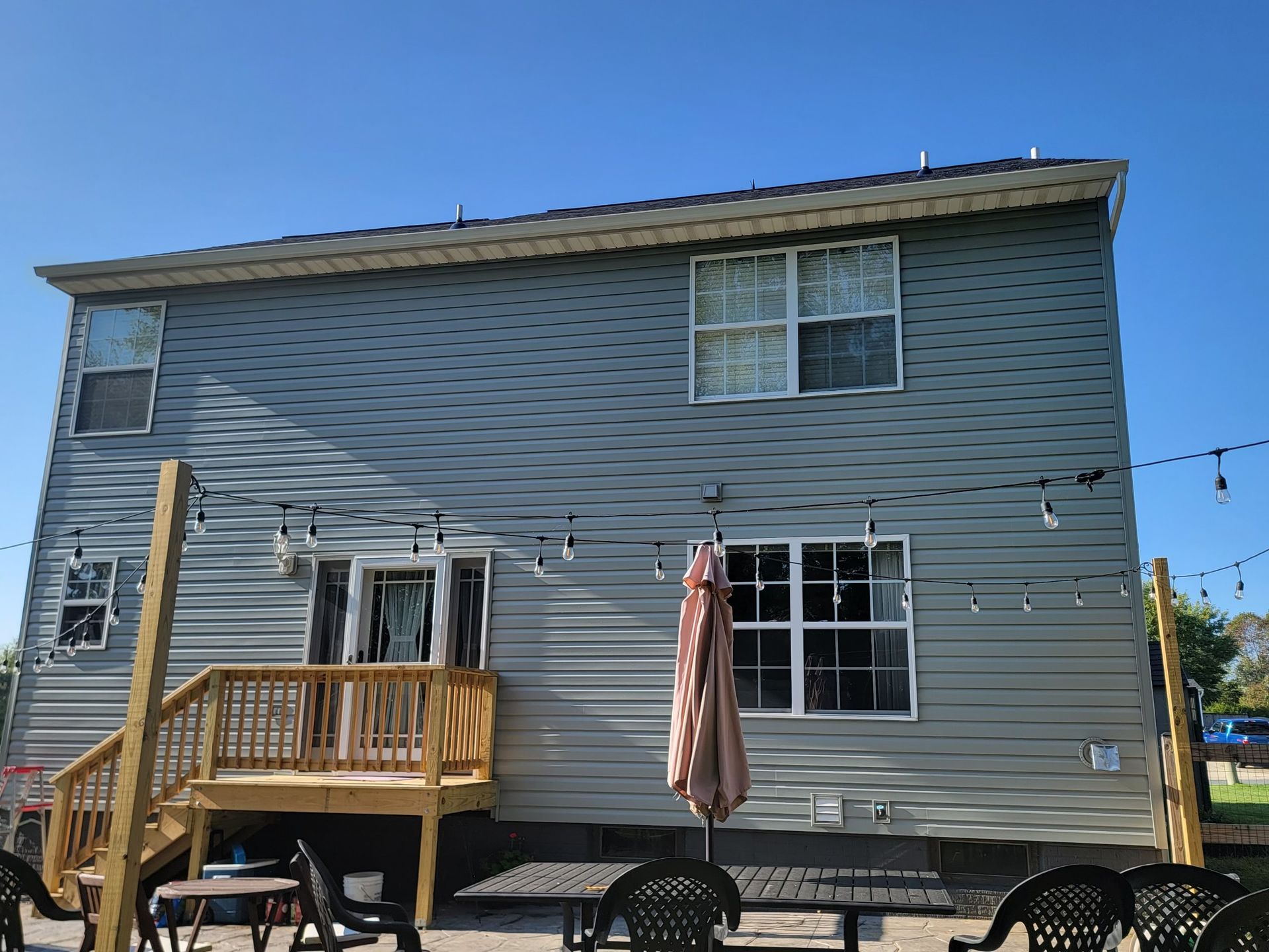 The back of a house with a deck and umbrella.