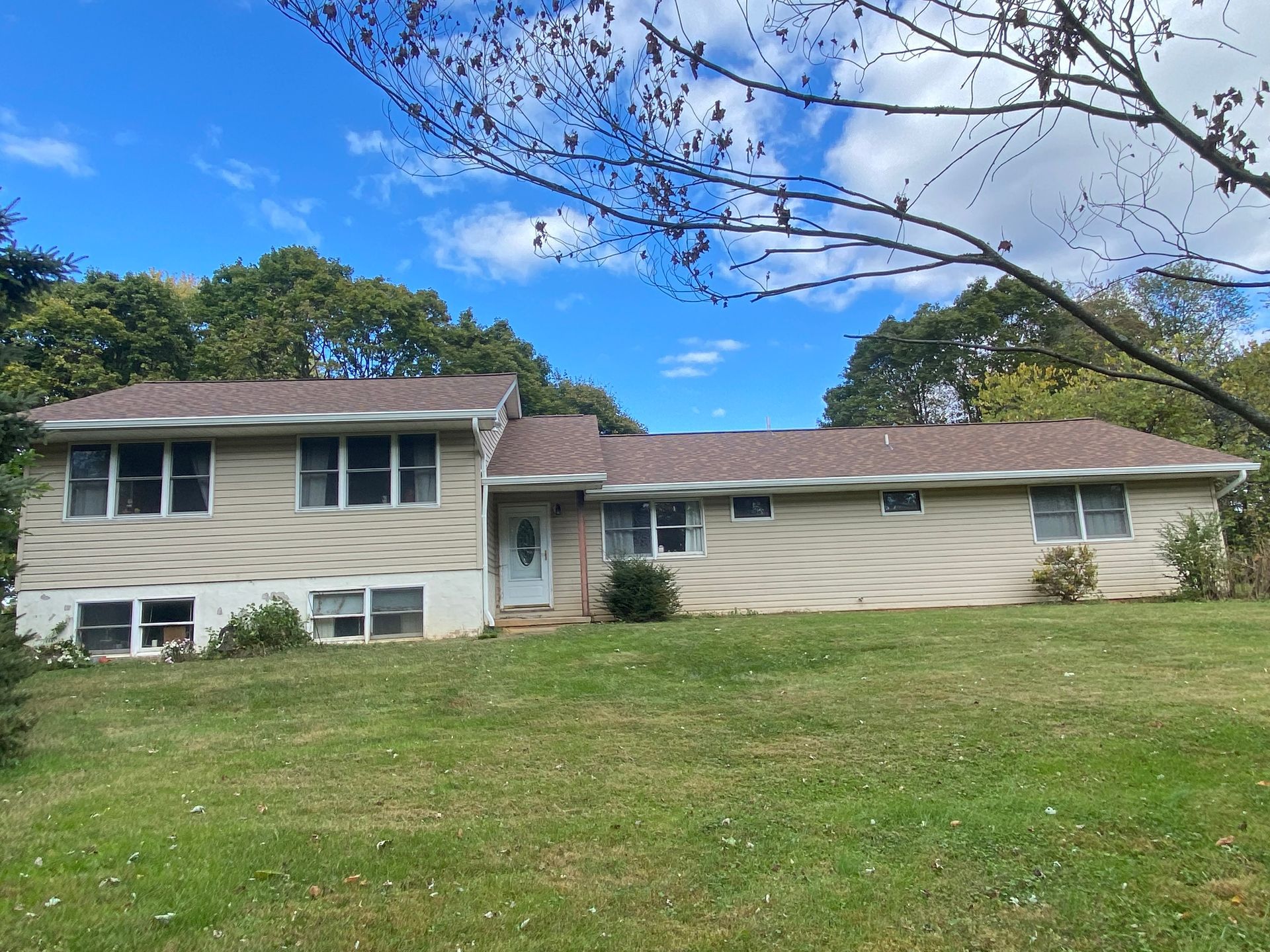 A house with a brown roof is sitting on top of a lush green field.