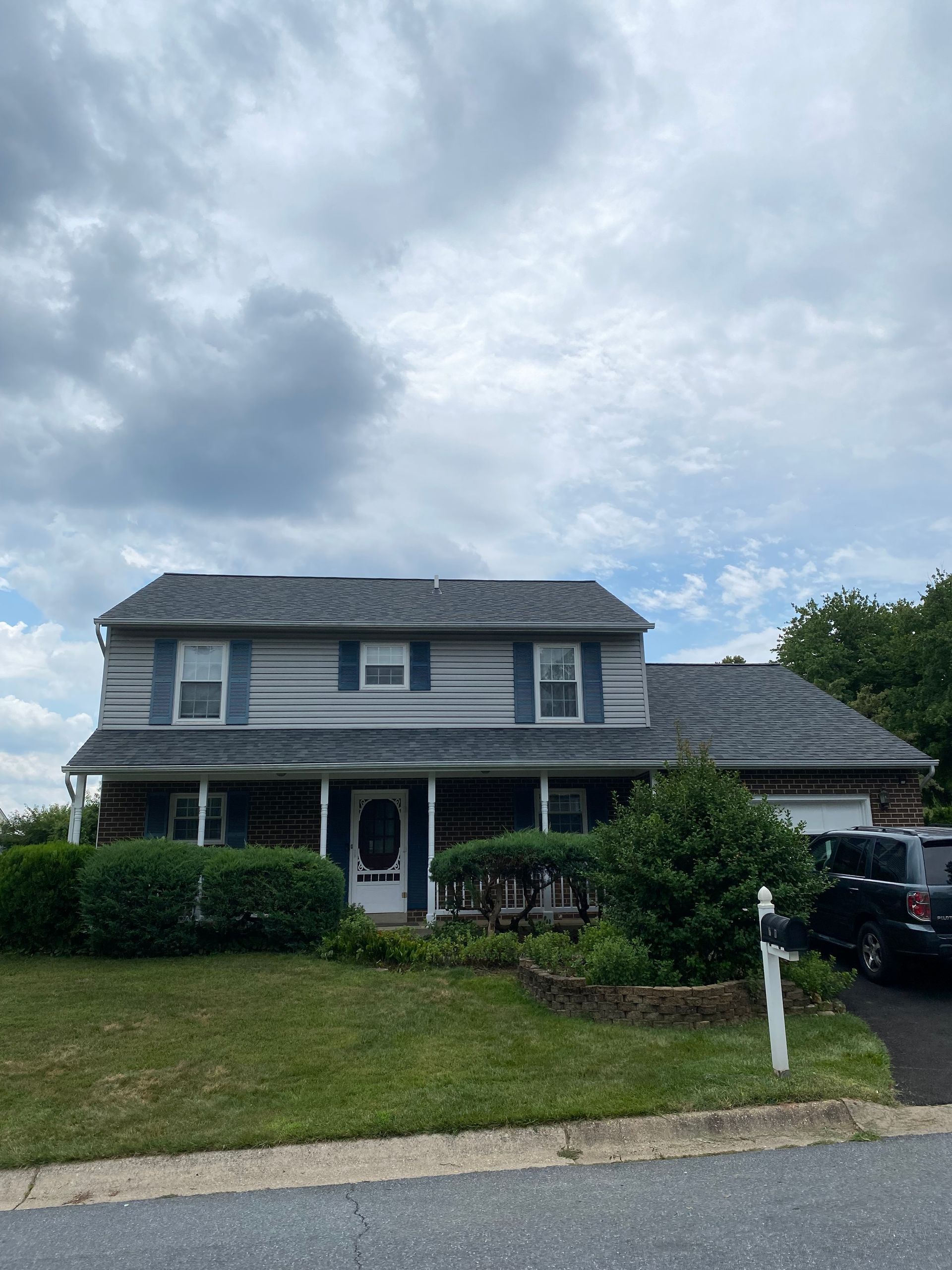 A large house with a car parked in front of it on a cloudy day.