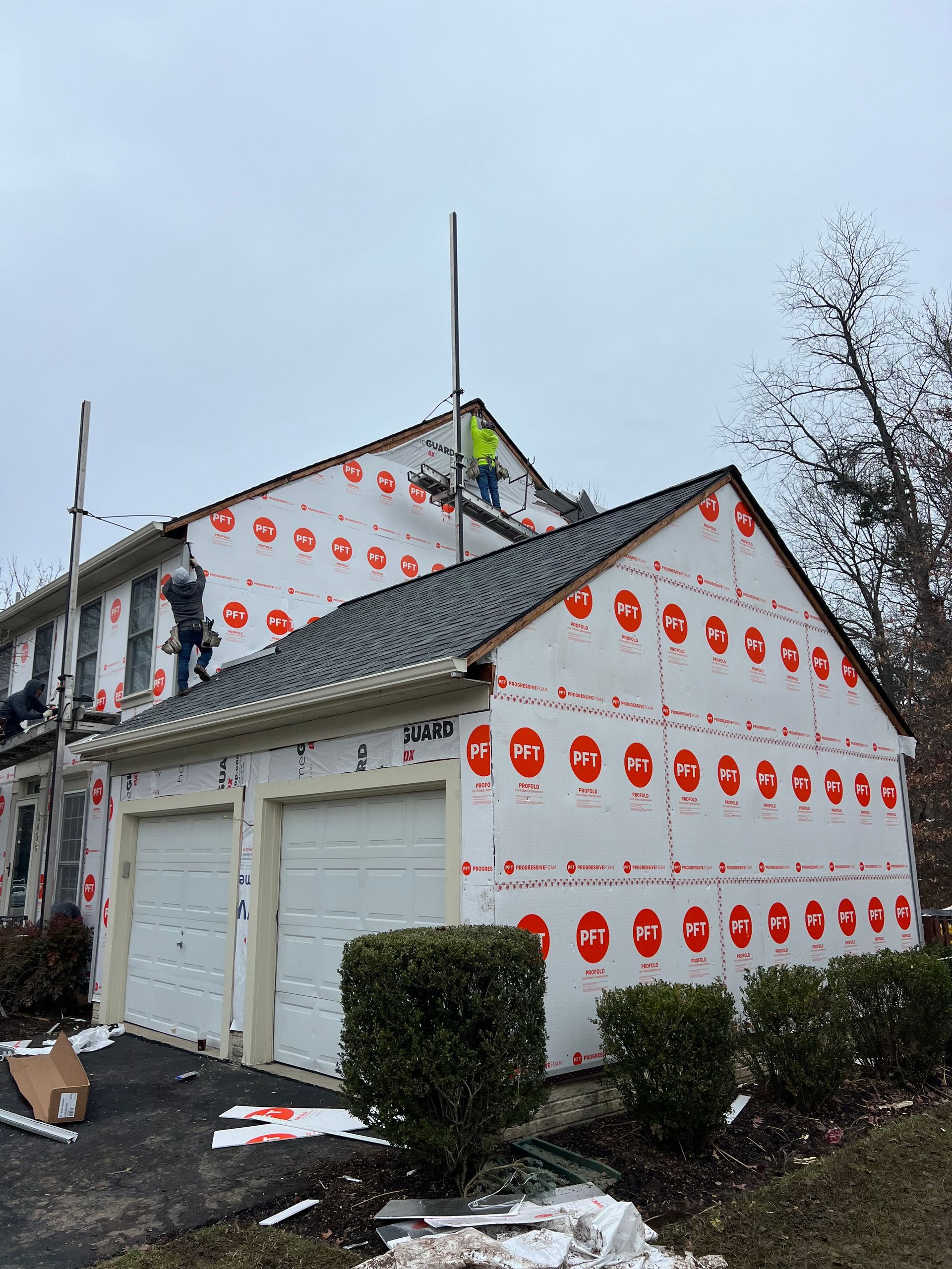 A man is standing on a ladder on the roof of a house.