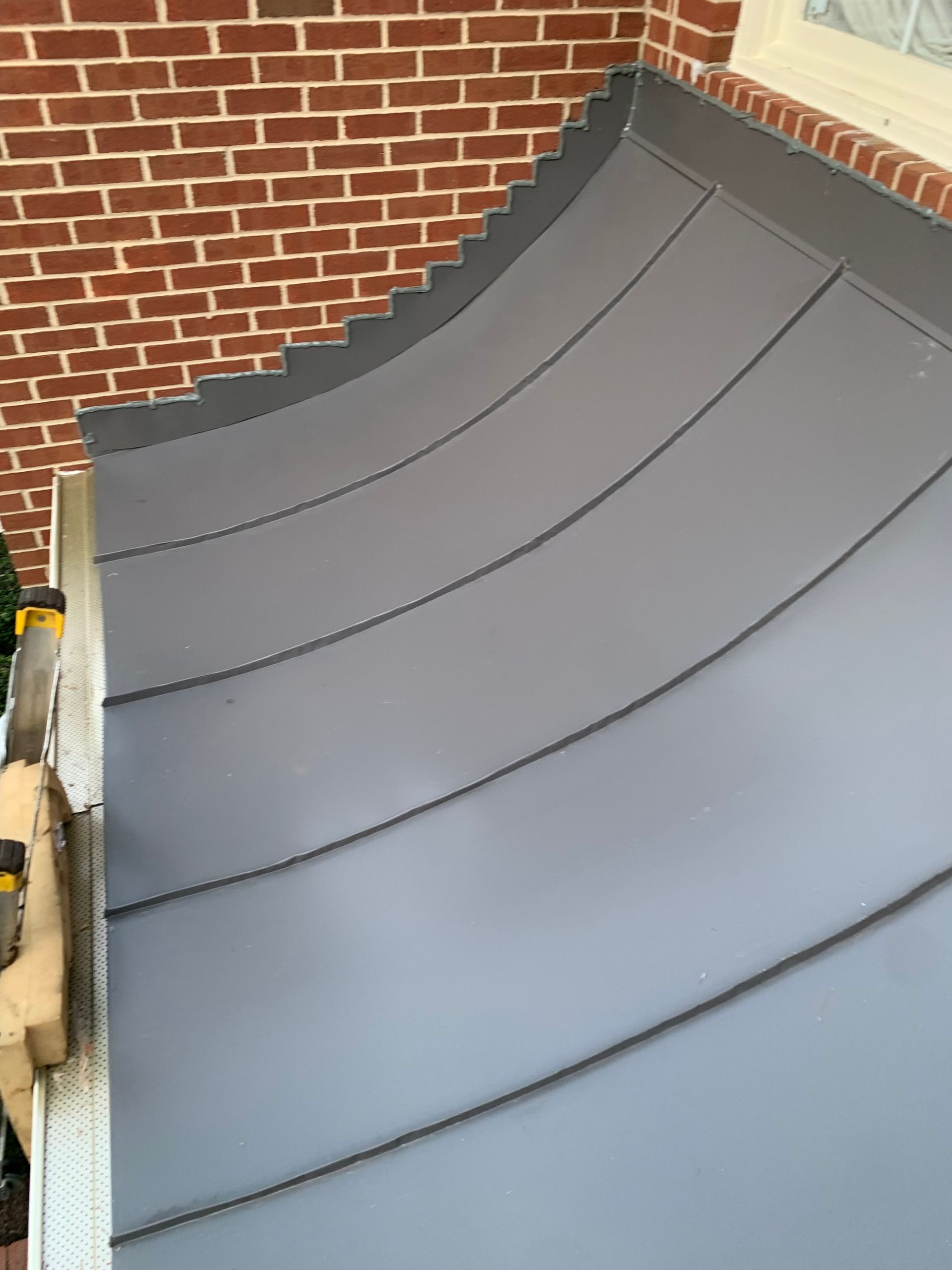A gray awning is sitting on the side of a brick building.