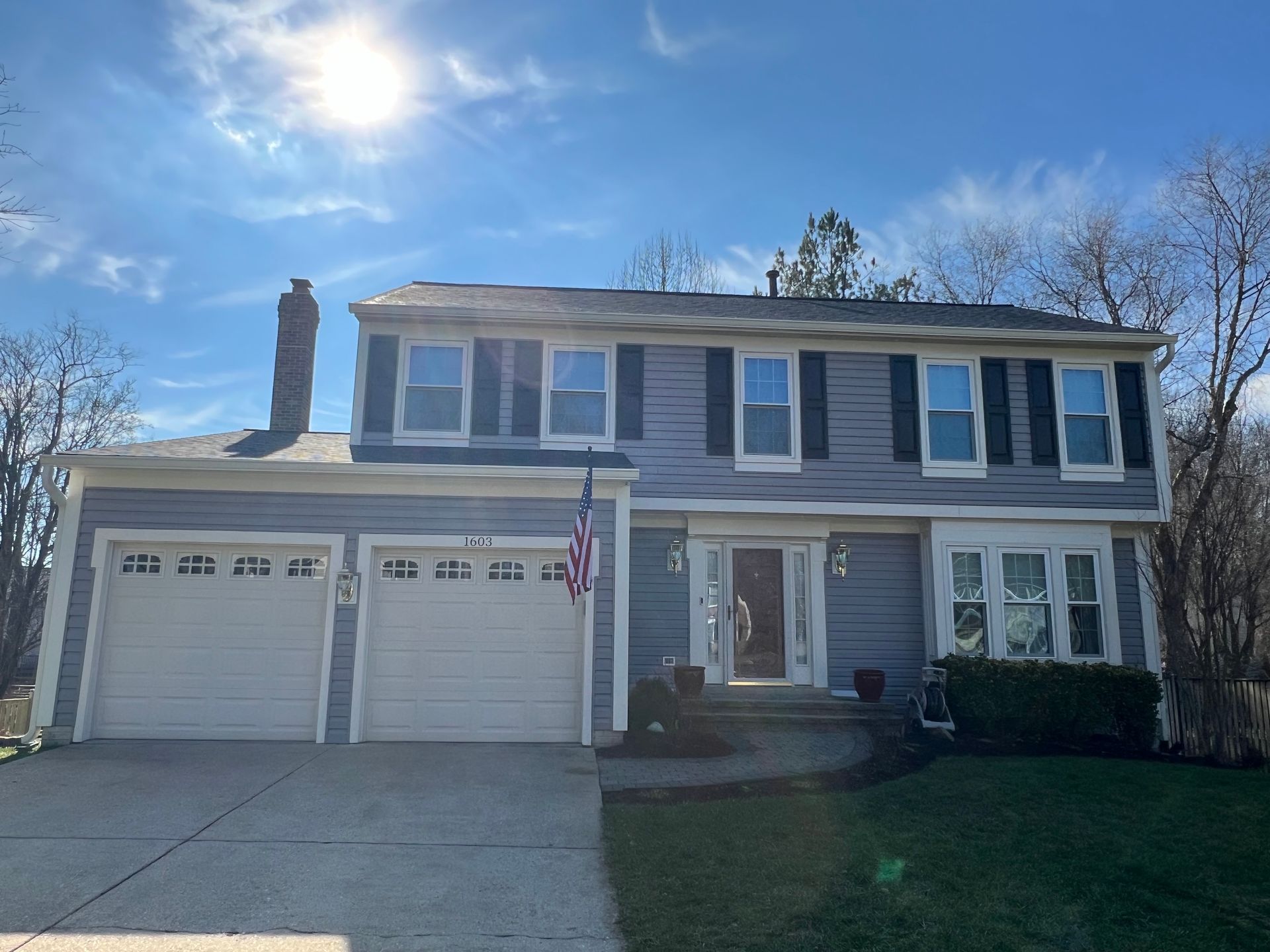 A large house with two garage doors and a flag on the front.