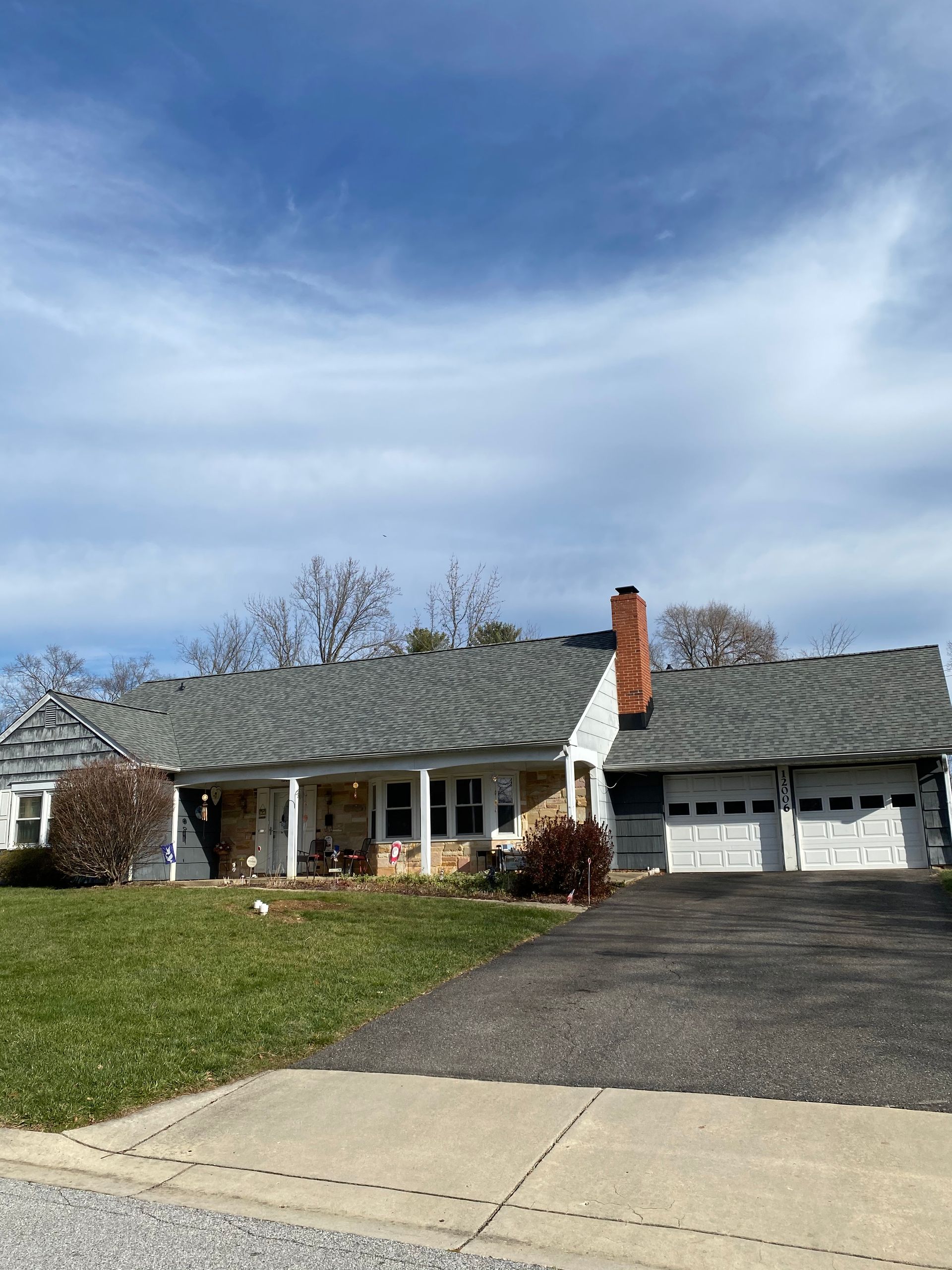 A white house with a gray roof and a red chimney.