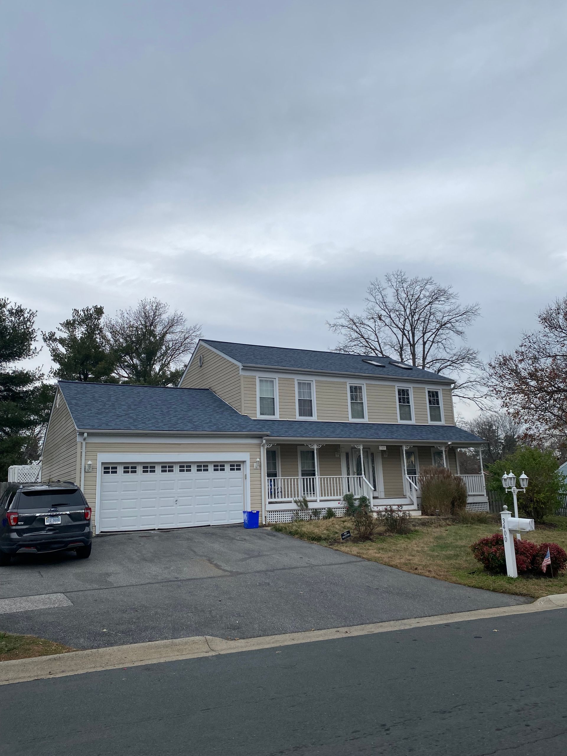 A house with a car parked in front of it on a cloudy day.