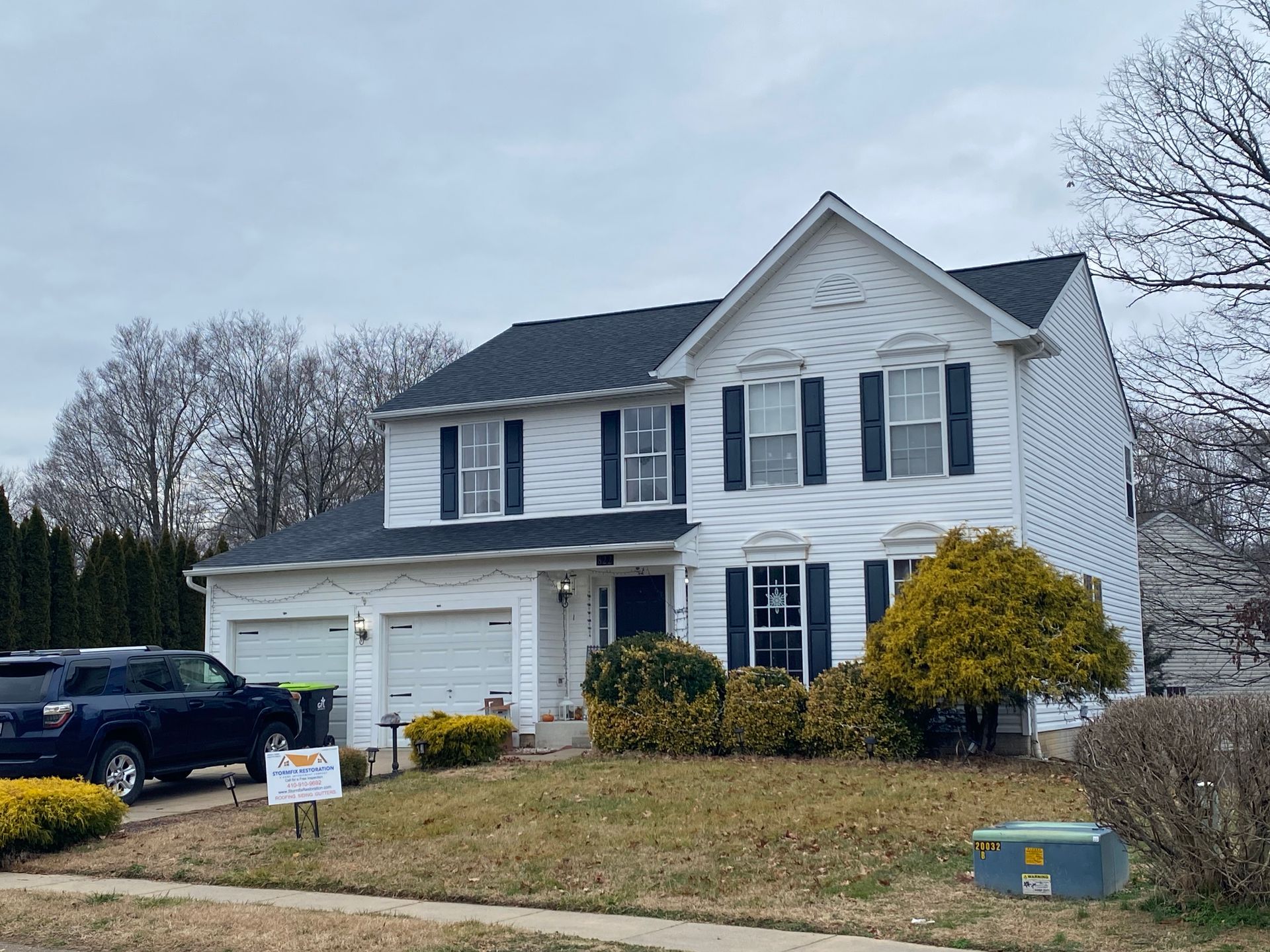 A white house with a black roof and black shutters is for sale.