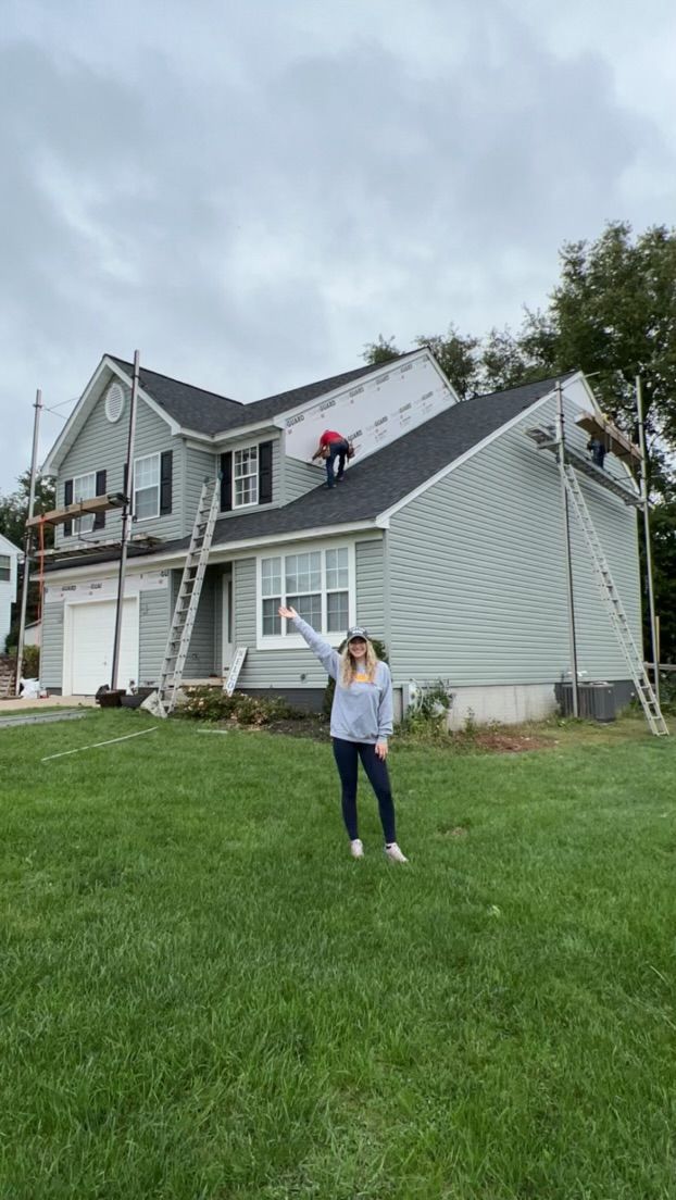 A woman is standing in front of a house under construction.