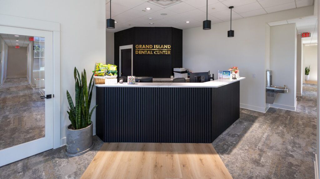 Reception area with black front desk, white countertop, plants, and wood flooring.