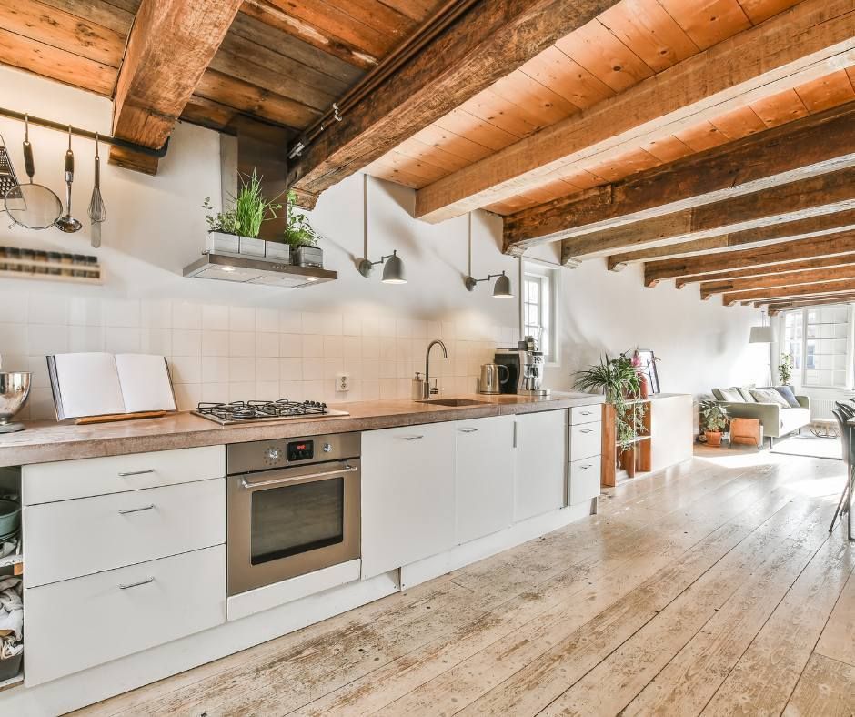 Kitchen with white cabinets, wooden beams, and a light-colored wood floor.