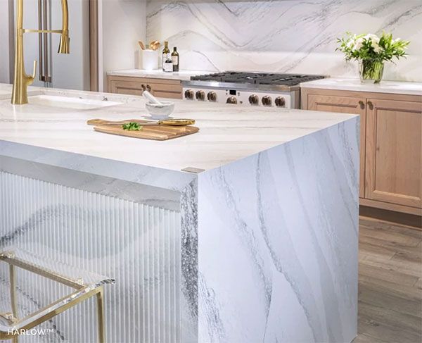 Modern kitchen with marble countertops, wood cabinets, and gold fixtures.