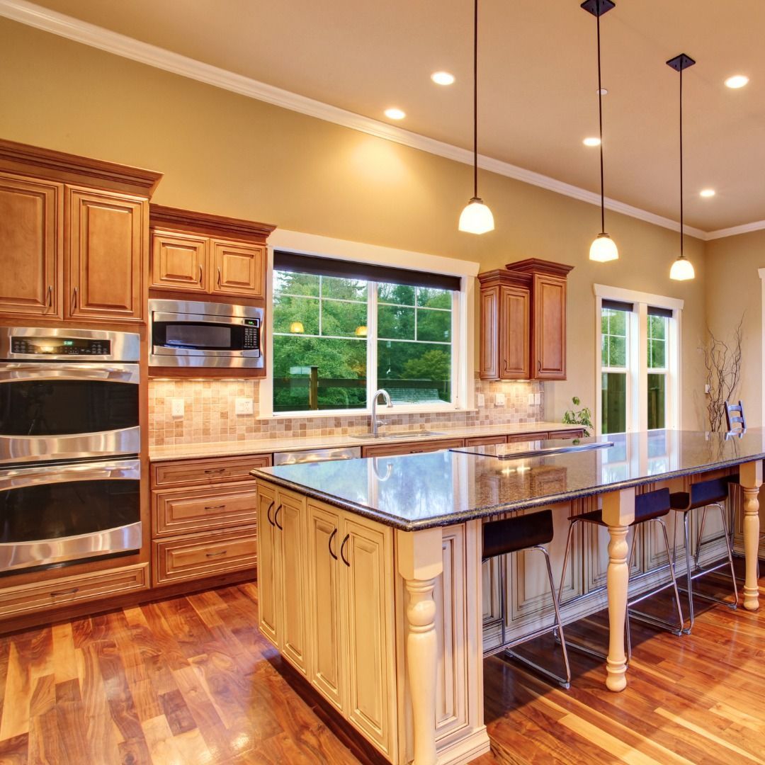 Kitchen with wood cabinets, island with stools, and pendant lights.