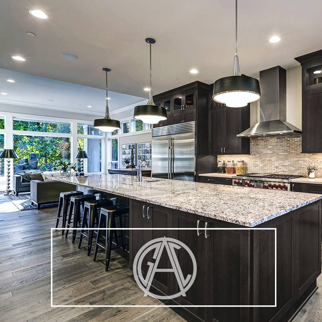 Modern kitchen with dark cabinetry, granite countertops, island with seating, pendant lights.