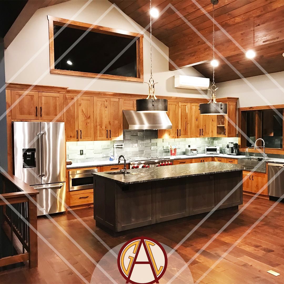 Modern kitchen with wood cabinets, stainless steel appliances, and a dark island.