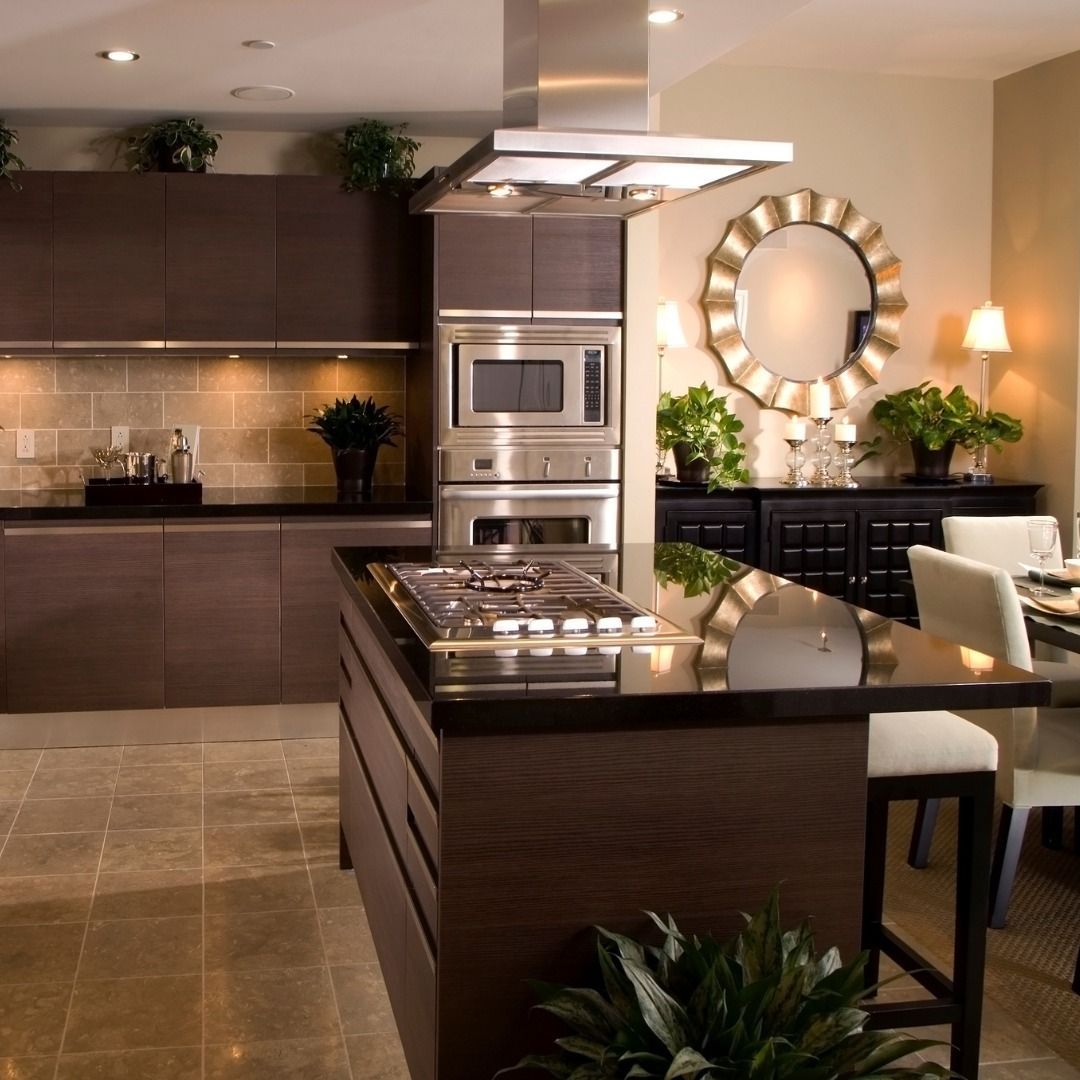Modern kitchen with dark brown cabinetry, stainless steel appliances, and island with cooktop.