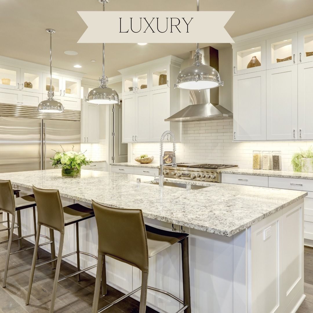 Luxury white kitchen with large island, granite countertops, and stainless steel appliances.