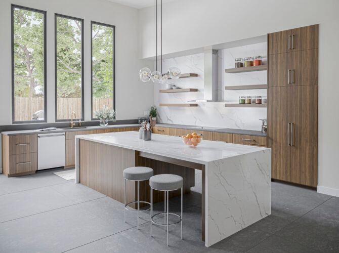 Modern kitchen with a large island, tall windows, and wood cabinetry.