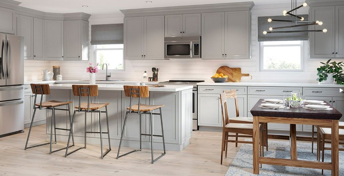 Modern kitchen with gray cabinets, white countertops, island with stools, and dining table.