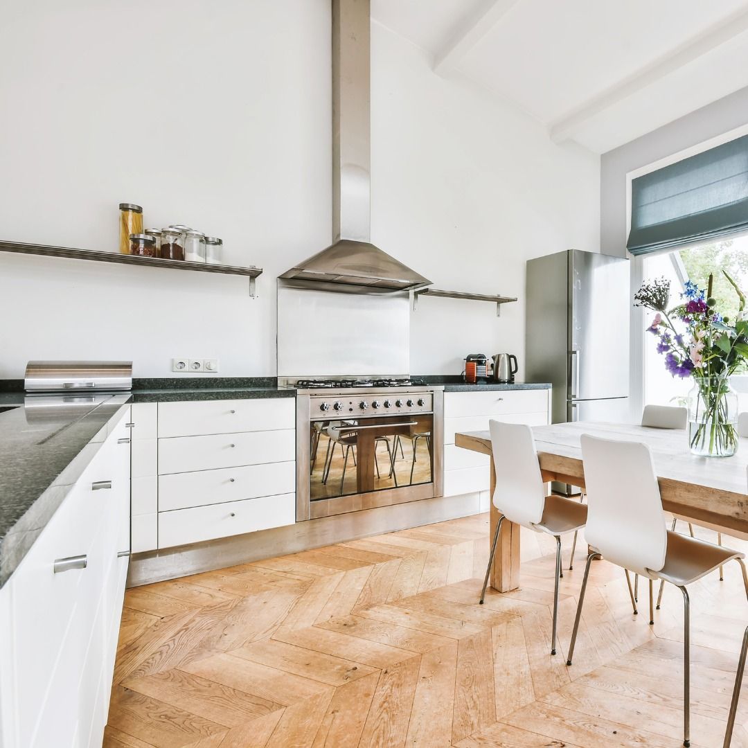 Modern kitchen with white cabinets, stainless steel appliances, and wooden flooring.