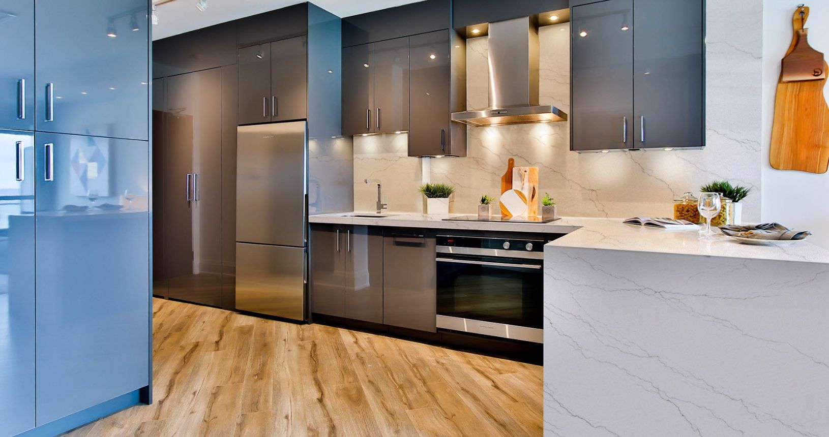 Modern kitchen with gray cabinets, stainless steel appliances, and wood flooring.