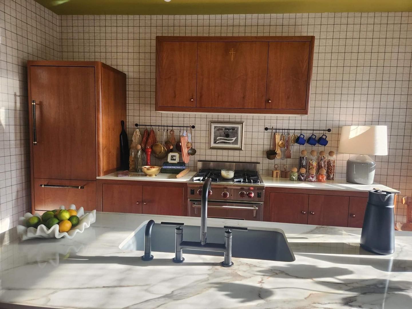 Kitchen with wood cabinets, white tiled walls, marble countertop, and stove.