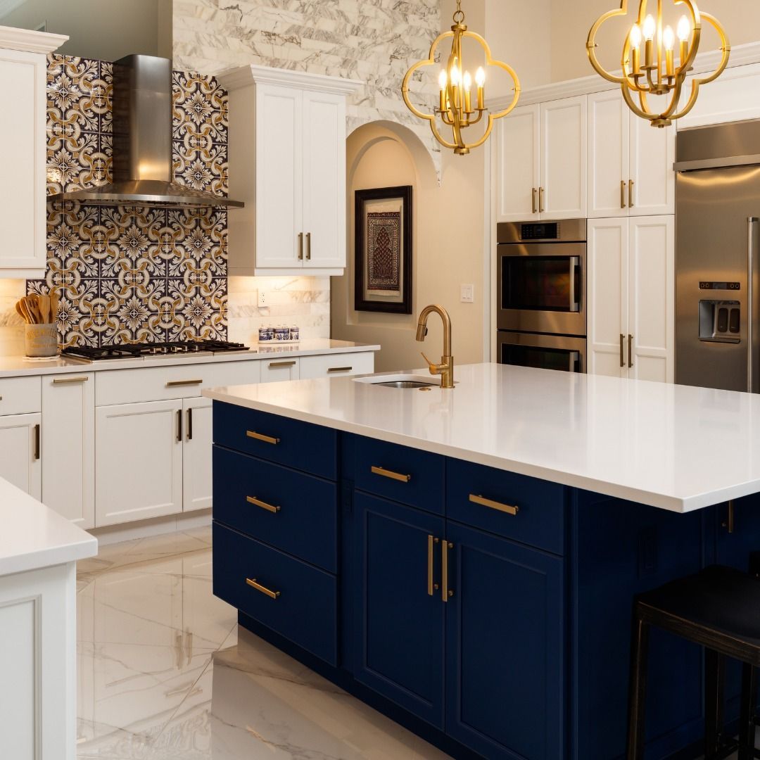 Elegant kitchen with white cabinets, blue island, gold accents, and patterned backsplash.