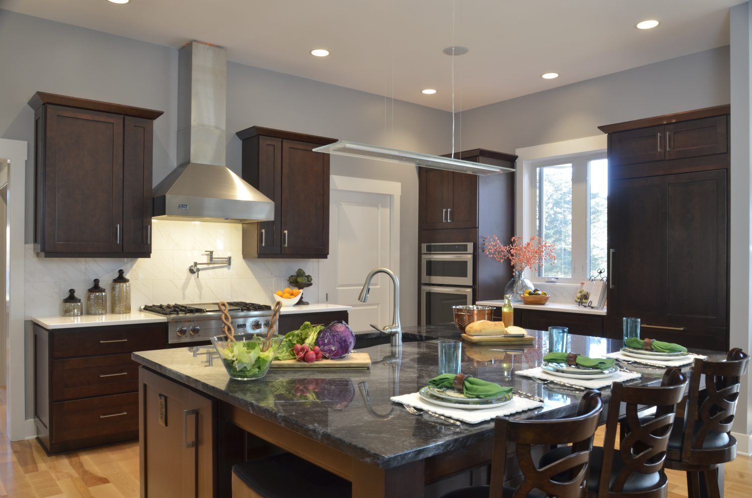 Modern kitchen with dark wood cabinets, stainless steel appliances, and a granite island with seating.