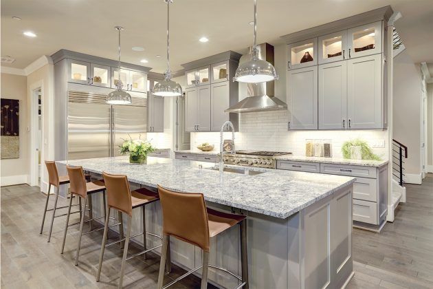 Modern gray kitchen with island, pendant lights, stainless steel appliances, and leather bar stools.